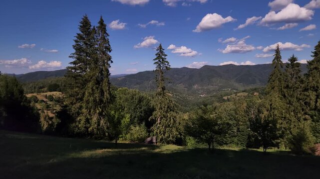  footage featuring a wide 30 fps panoramic shot of a vast green mountain valley under a deep blue sky with scattered white fluffy clouds. Ideal for travel documentaries, nature projects,