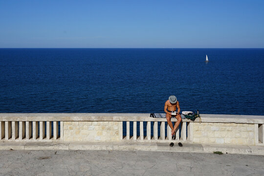 Man reading  book on seaside terrace near Passetto beach in Ancona, Italy