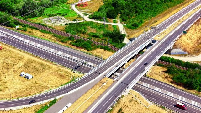 Roadways connect in a rural area. Multiple roadways intersect in a rural setting with green spaces and train tracks visible nearby.