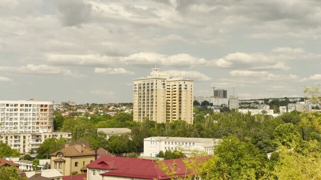 High-rise apartment buildings stand tall above green trees in Simferopol, Crimea. The peaceful cityscape rests under a cloudy sky. The bright scene brings a quiet sense of hopeful serenity.