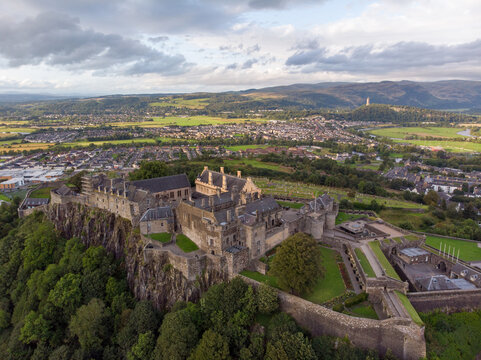 Aerial view of Stirling Castle perched on a volcanic crag overlooking the city with historic stone walls and lush green trees in Stirling, Scotland, United Kingdom.
