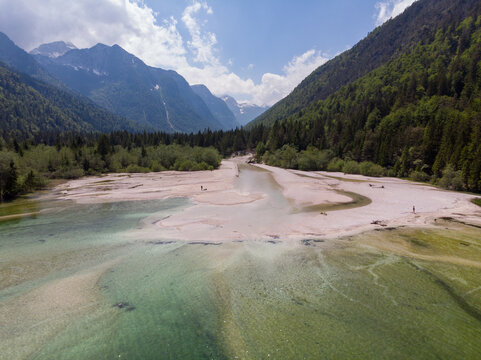 Aerial view of Lago del Predil with its clear turquoise water, sandy shores, and surrounding lush green forests and mountains in Tarvisio, Friuli-Venezia Giulia, Italy.