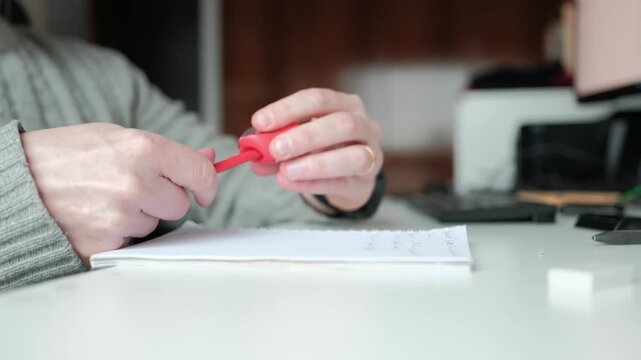 Person sharpening red pencil before writing on paper