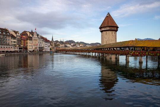 Lucerne, Switzerland - 01 November 2018: View of the historic Chapel Bridge and Water Tower spanning the Reuss River in Lucerne, with traditional buildings along the waterfront.