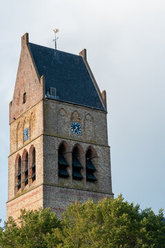 Clock tower stands tall against the sky in a quiet town during late afternoon