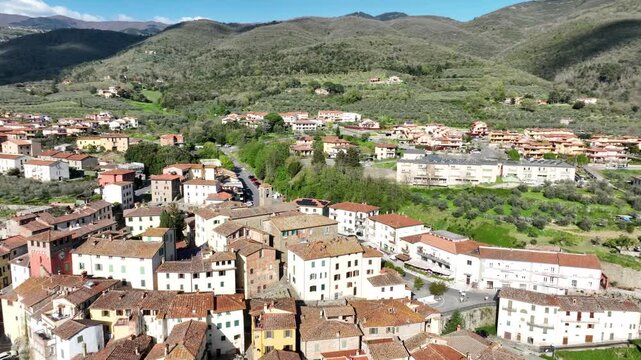 Aerial view of the historic village of Loro Ciuffenna with stone buildings, terracotta rooftops, and lush green hills in the background in Loro Ciuffenna, Tuscany, Italy.