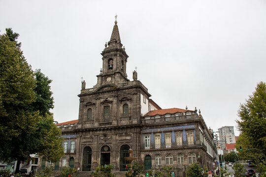 Porto, Porto District, Portugal - 14 August 2017: View of the historic Igreja dos Congregados with its ornate stone facade, bell tower, and traditional blue tile decorations under an overcast sky.