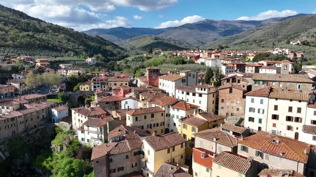 Aerial view of the historic village of Loro Ciuffenna with stone buildings, terracotta rooftops, and lush green hills in the background in Loro Ciuffenna, Tuscany, Italy.