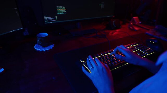 Female hacker coding in dark room with neon lights