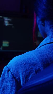 Female hacker coding in a dark room at night