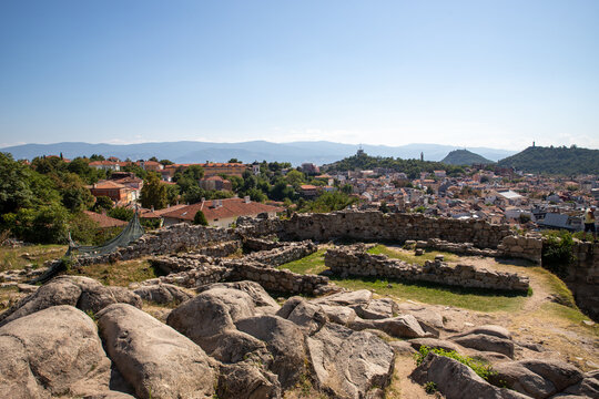 Plovdiv, Plovdiv Province, Bulgaria - 24 August 2018: View of the ancient ruins of Nebet Tepe overlooking the historic city rooftops and surrounding hills under a clear blue sky.
