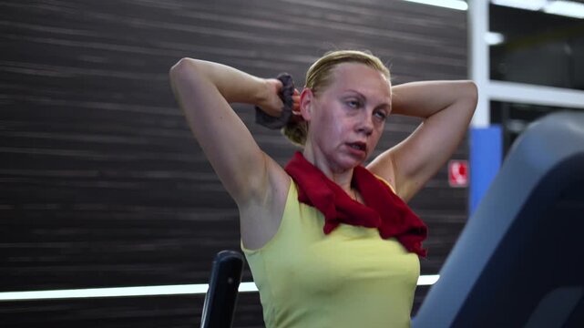 A middle-aged woman at the gym. She wears her hair in a ponytail while working on a step machine, embodying the essence of physical education.
