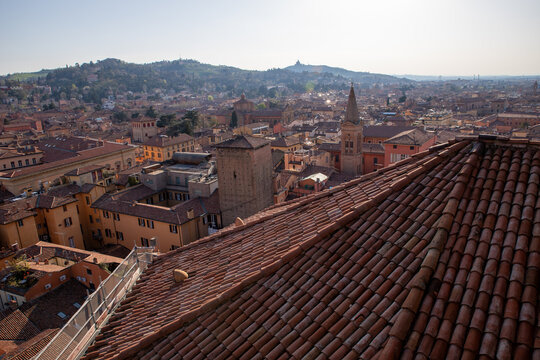 Bologna, Italy - 07 April 2018: View of the historic city skyline with terracotta rooftops, medieval towers, and distant hills under a clear sky.