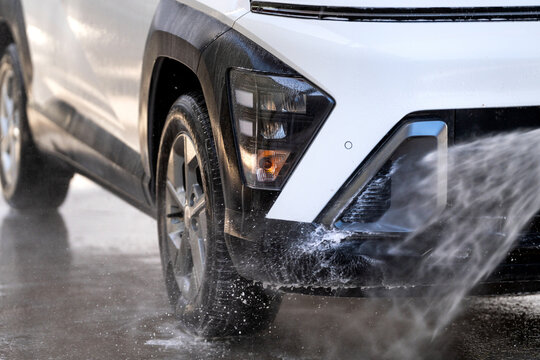 Car washing at a self-service station, water spray cleaning vehicle bumper