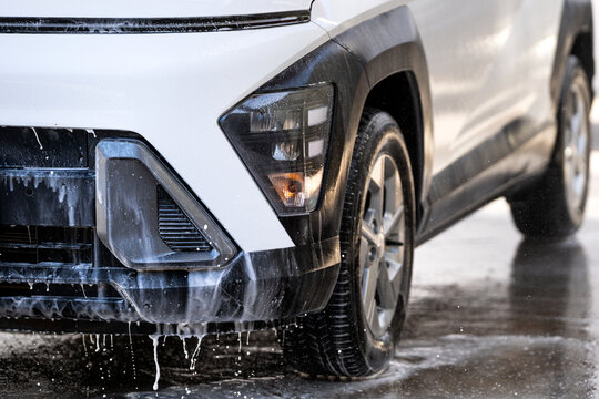 Car covered in white foam and soap during a professional washing service