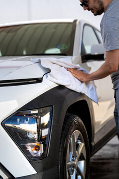 Man wiping down his white vehicle, ensuring a spotless finish after a car wash