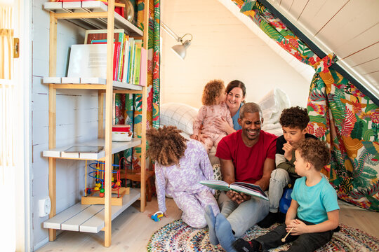 Parents reading a story to children in cozy attic playroom