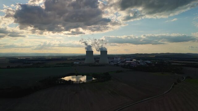 Aerial view of Temelin nuclear power plant. Large cooling towers emitting steam over a rural landscape at sunset