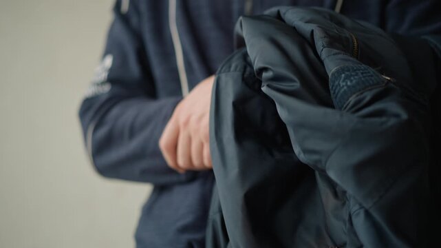 Close up of man holding and examining dark blue fabric material likely clothing or textile. man hands are visible as they manipulate soft texture with subtle movements showcasing details