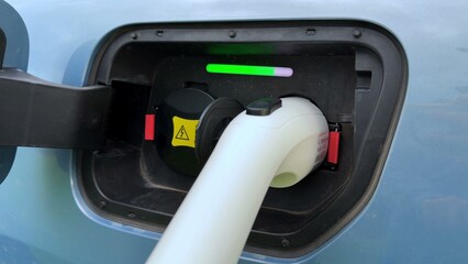 Plakat Charging port on electric vehicle with connected cable and colored indicator lights showing status