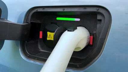 Charging port on electric vehicle with connected cable and colored indicator lights showing status © NBLX