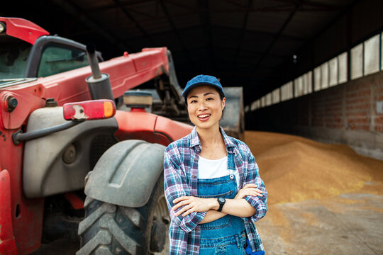 Smiling farm worker by tractor in grain storage barn
