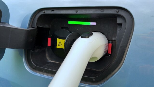 Charging port on electric vehicle with connected cable and colored indicator lights showing status