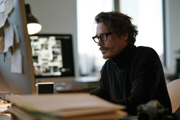 Obraz premium A stylish man analyzes creative work in a contemporary office filled with notes and designs, showcasing commitment and passion for the artistic process.