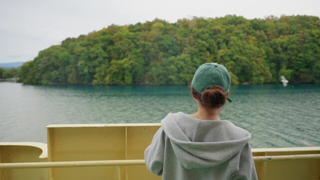 Young woman standing on deck of tour boat on Lake Toya in Hokkaido, Japan, scared of seagulls flying around trying to snatch food from tourists during sightseeing tour in lake. Funny video of tourist