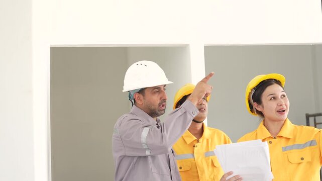 Construction workers pointing upward while discussing building work, site inspection, project planning, engineering communication, construction teamwork, structural assessment.