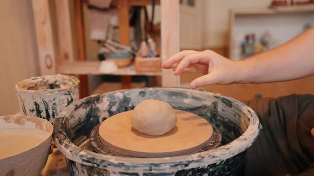Throwing wet clay onto pottery wheel
