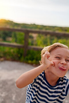 Playful young boy making a funny face, sticking out tongue and pulling cheek, showing humorous expression