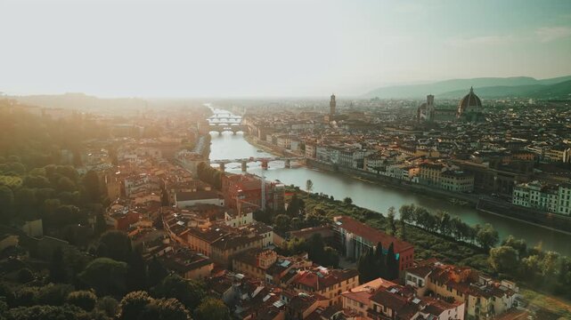 Sweeping aerial follows the Arno through Florence, revealing Ponte Vecchio, riverside palaces, Palazzo Vecchio and the distant Duomo.