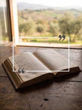 Open vintage bible book on wooden table with white quote box overlay and nature view.