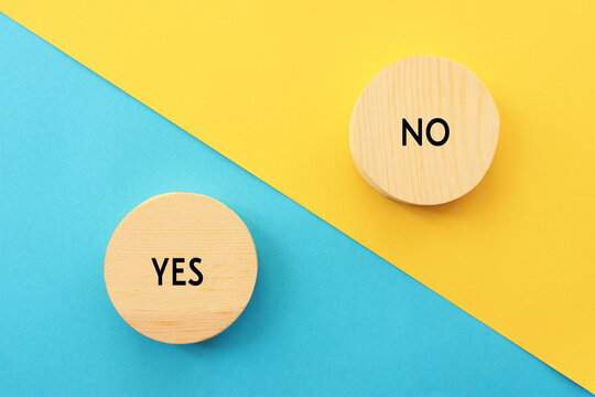 wooden cubes with the text yes or no on pastel paper background