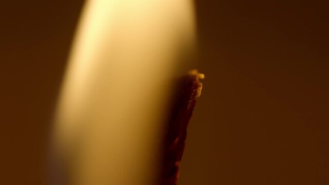 Candle wick glows softly in warm amber light with a blurred dark background.
