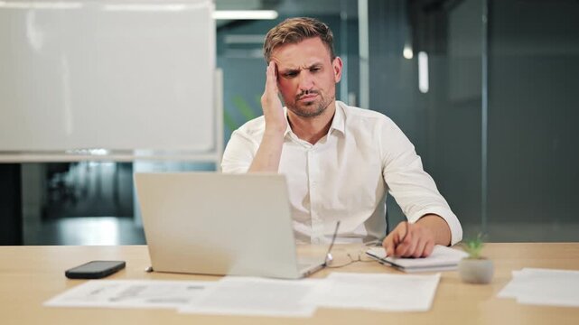 Professional experiences intense headache from prolonged computer work. Business pressures contribute to discomfort. Individual seeks relief, signs of burnout and eye strain within office environment.