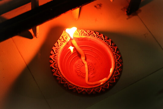 Lit Clay Diya Oil Lamp Glowing in Dark Diwali Festival Background. Traditional Indian Clay Diya Lamp for Diwali Celebration Rituals Decorative Terracotta Diya with Flame for Hindu Puja and Deepavali.