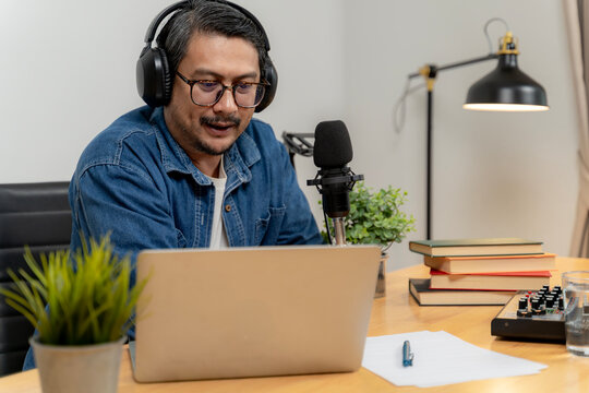 A young man speaks into a microphone while recording and broadcasting an audio podcast in a studio.