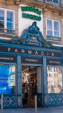 Historic Blue Pharmacy Shopfront with Bowl of Hygieia Serpent Emblem, Founded 1804, Porto, Portugal &mdash; Concept: Heritage Retail Design, Pharmacy History and Multilingual Tourism Signage