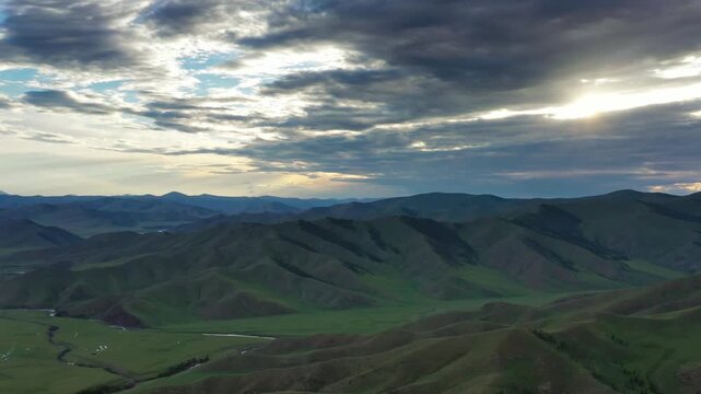 Aerial view of the Orkhon Valley Natural and Historical Reserve with rolling green hills and dramatic sunset clouds in Xarxorin, Ovorkhangai, Mongolia.
