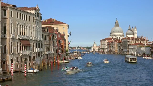 View of the Grand Canal with historic buildings and boats passing by the Santa Maria della Salute basilica in Venice, Veneto, Italy.