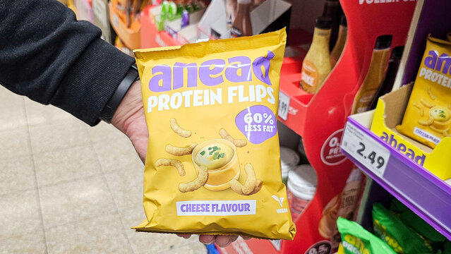 Hand holding ahead protein flips snack in store