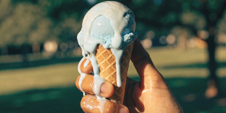 Global warming and climate change with hands holding an ice cream cup with melting blue ice cream