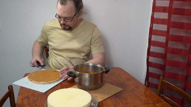 Man spreading waffle cakes with condensed milk. Make cake cream. Sweet food.