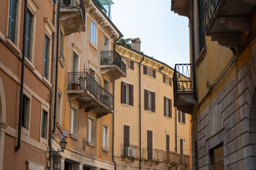 Fototapeta premium Charming narrow Street with Historic house Buildings and Balconies in Old Town Verona, Italy.