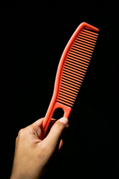 Close up of hand holding hair comb isolated on black background