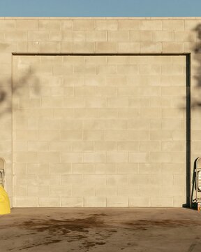 Blank display banner mockup on a grey breeze-block wall in a lived-in garage with oil-stained concrete floors for branding and design