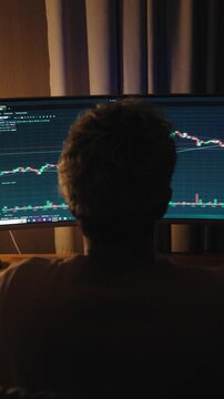 A man sits comfortably at home working on a computer and editing video footage. The scene shows a modern creative workflow with video editing software, timeline adjustments