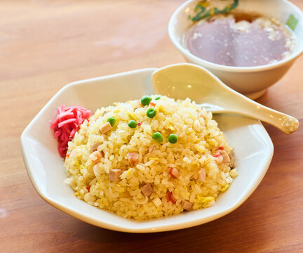 Japanese style fried rice chahan with green peas and pickled ginger on wooden table